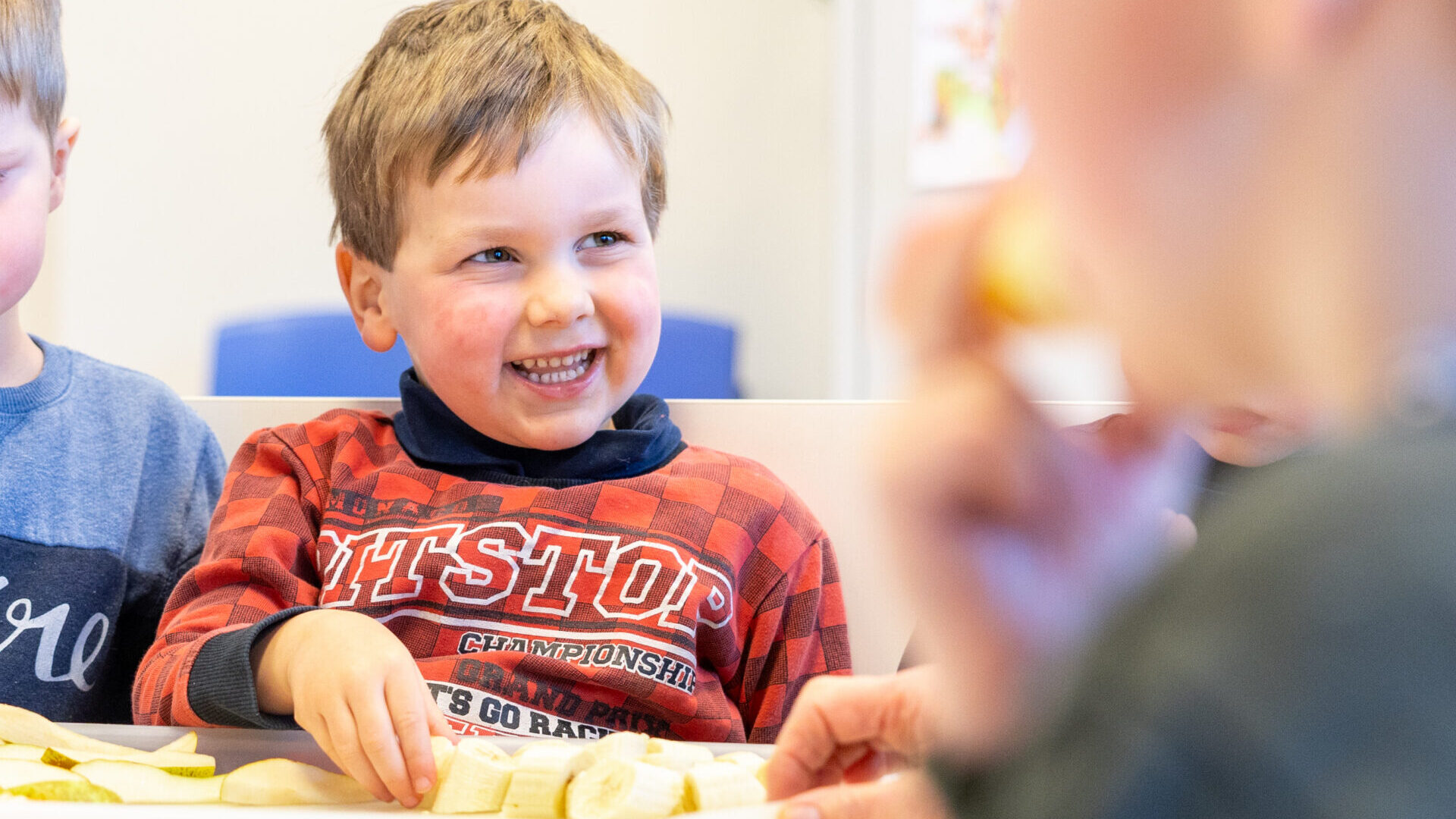Jongen van het kinderdagverblijf op Aquamarijn pakt vrolijk gezond eten.